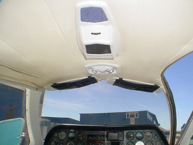 View from inside the cockpit showing the overhead panel, sun visors, and the top of the instrument panel with gauges.