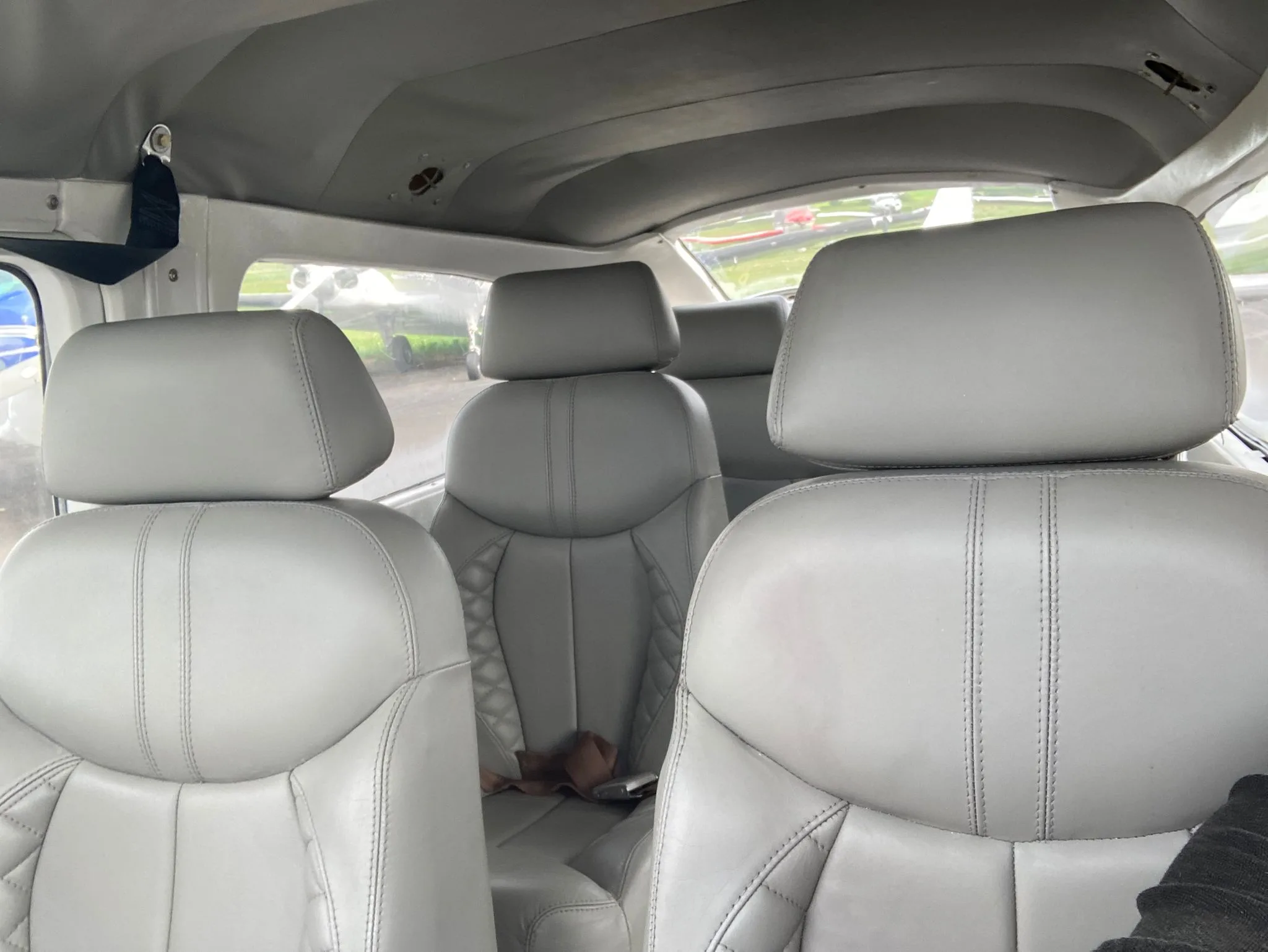 A view of the aircraft's light grey leather rear passenger seats from the back, looking towards the front.