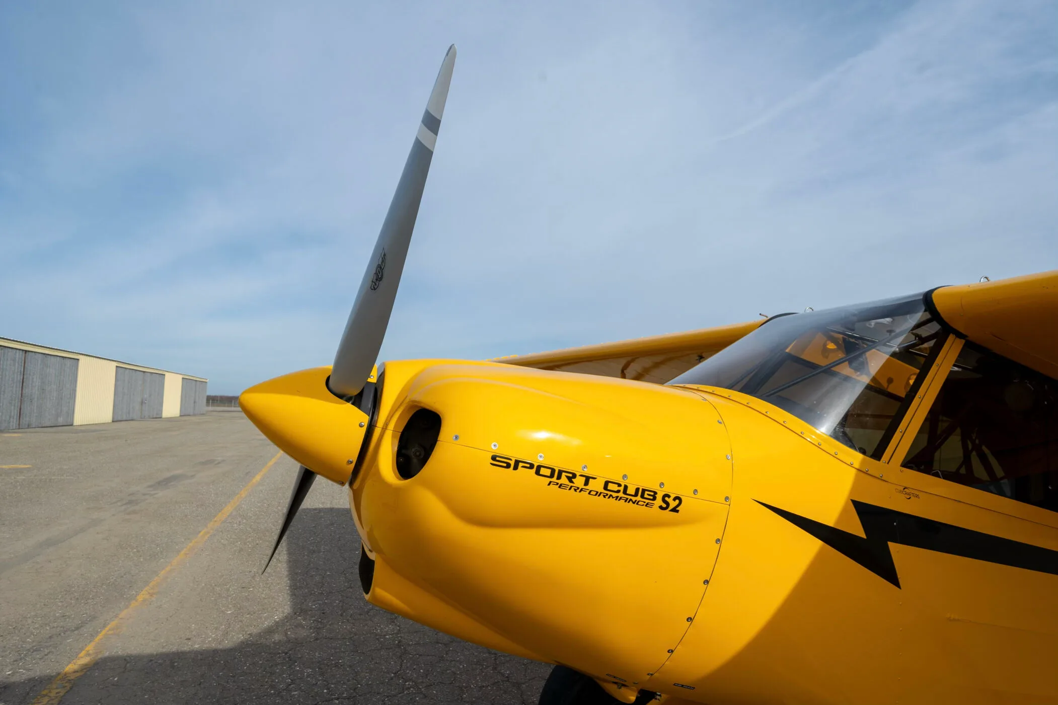 A close-up view of the propeller and front fuselage of the yellow CubCrafters Sport Cub S2 aircraft.