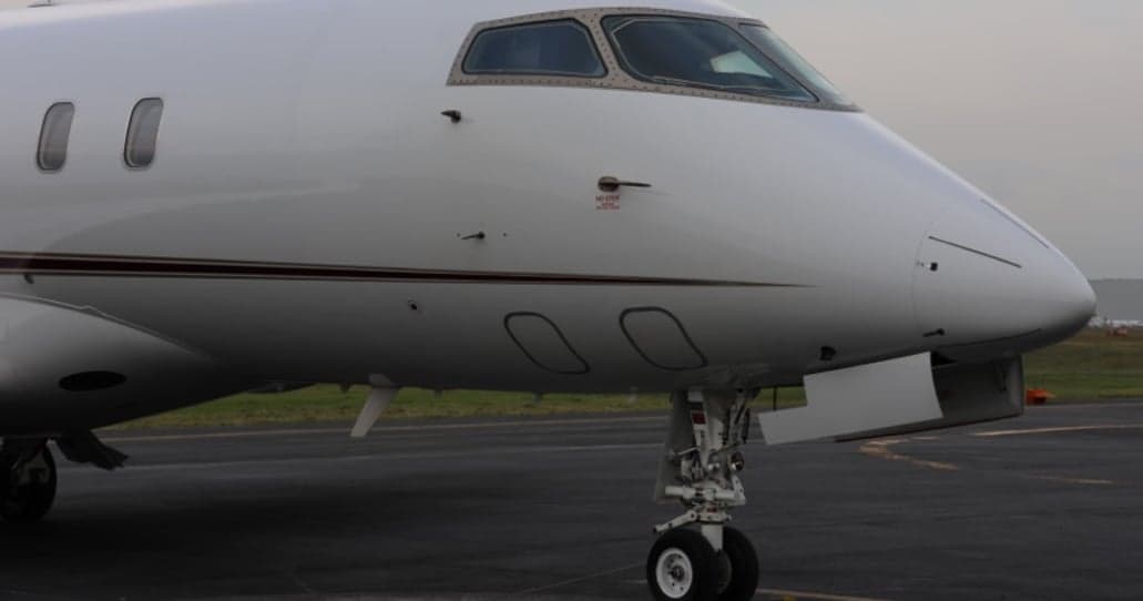 Close-up of the nose and landing gear of a white jet aircraft.
