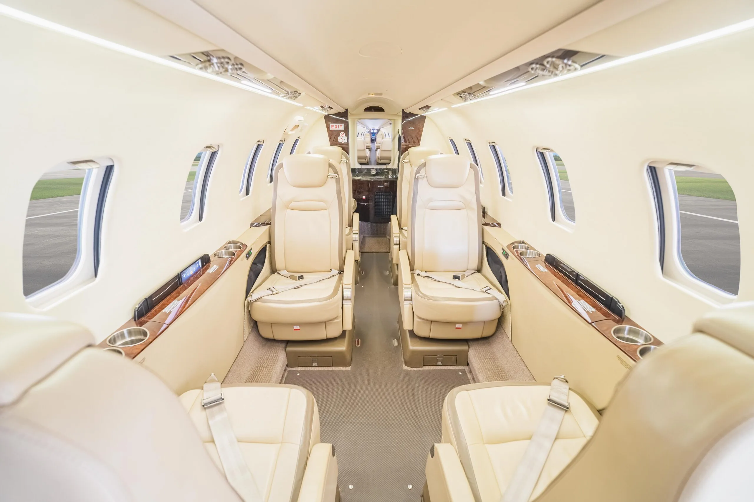The interior of the aircraft features cream-colored leather seats and wood accents.