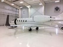 Side view of a Learjet parked inside a hangar with a shiny floor.