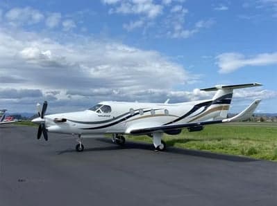 Pilatus PC-12 on the tarmac with a white and brown paint scheme.