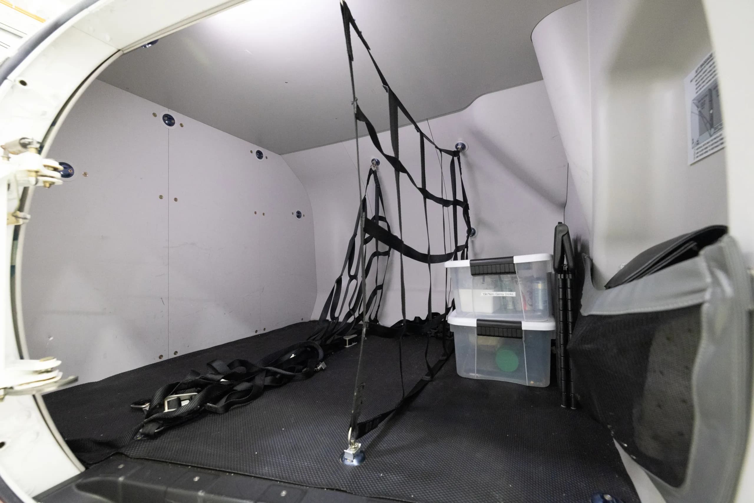 The open aft baggage compartment of a HondaJet, equipped with cargo netting and clear storage bins.