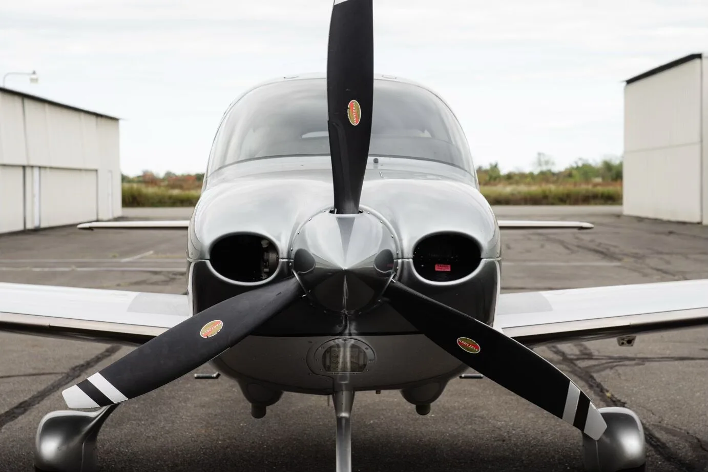 A close-up front view of the propeller and nose of the silver Cirrus SR22 GTS Platinum aircraft.