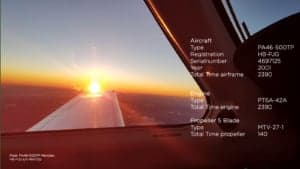 View from inside the aircraft with the wing and sunset in the background, along with aircraft information.