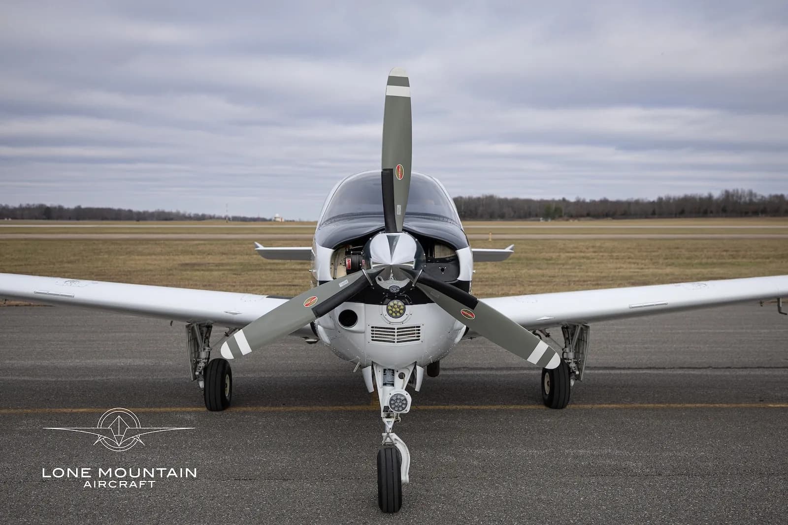 A head-on view of the N721EN single-engine propeller aircraft, showing its propeller and nose landing gear on an airfield.