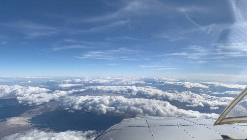 View from the cockpit of an aircraft flying above the clouds.