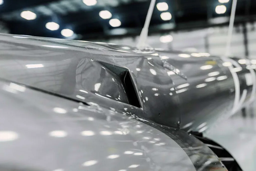 A close-up view of an air intake vent on the grey fuselage of a helicopter.