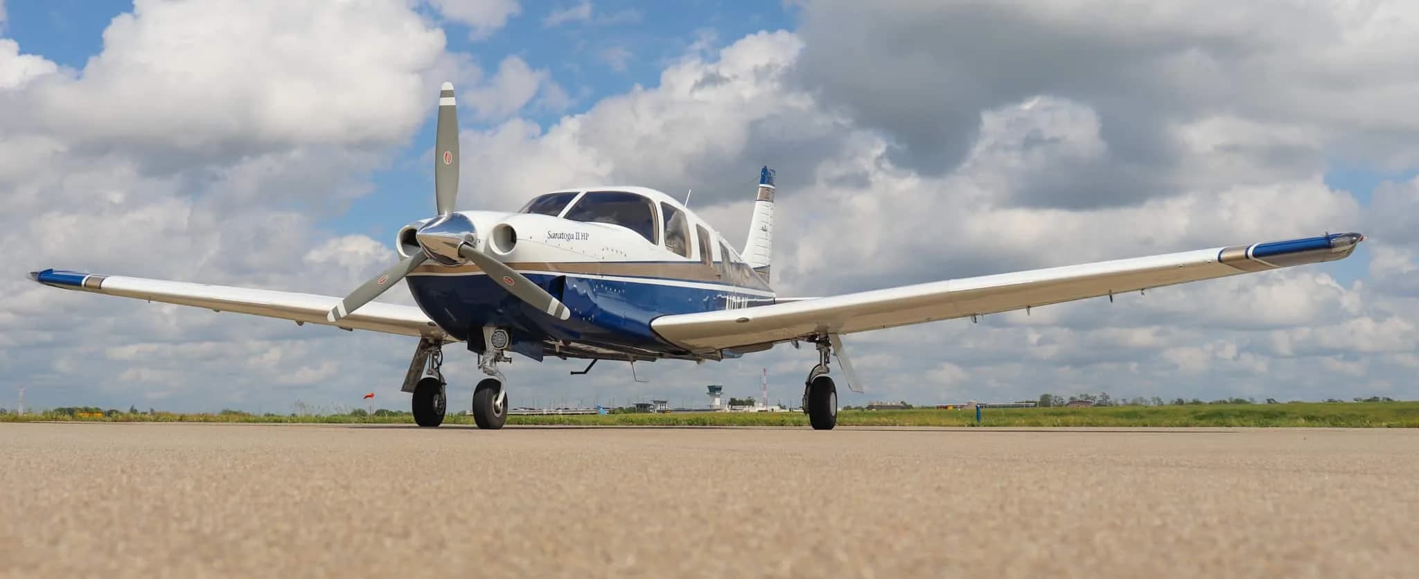 A low-angle front view of the Piper Saratoga II HP aircraft, N954K, showcasing its full wingspan on an airfield.