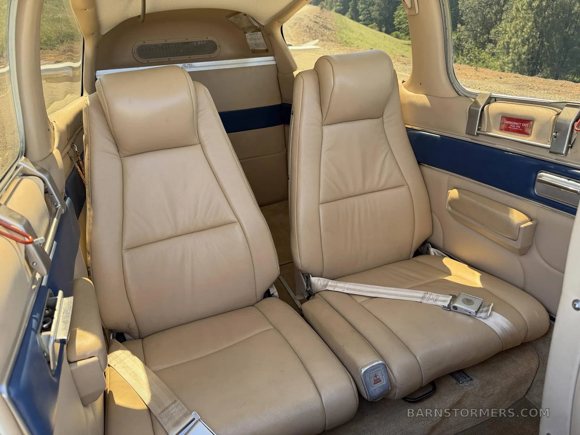 The tan leather rear seats of a small aircraft cabin.