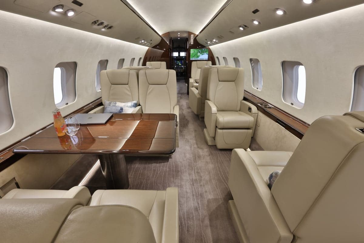View of the Bombardier Global Express cabin interior with leather seating and a table.