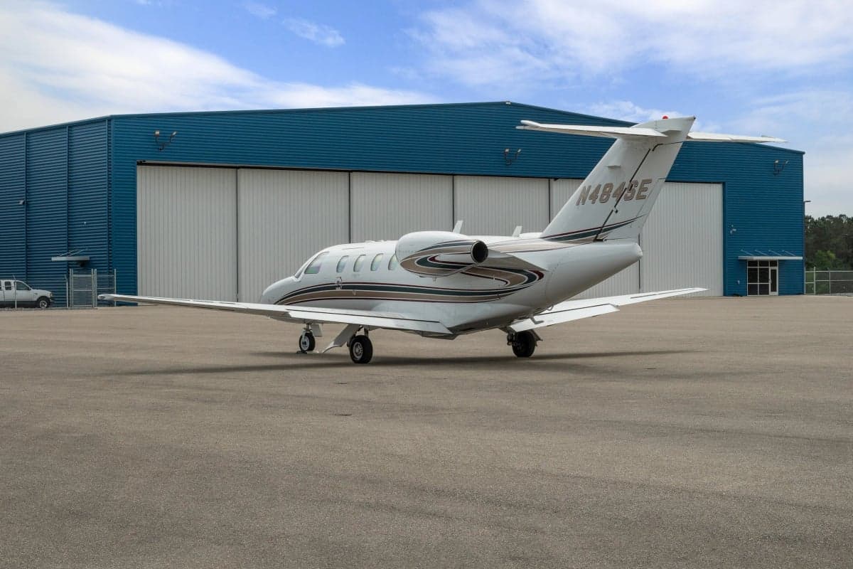 Rear view of a Cessna Citation CJ1 parked in front of a hangar.
