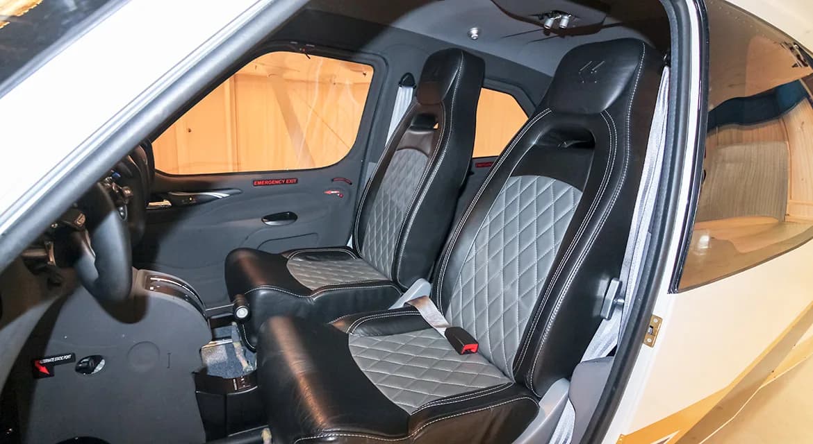 The interior of the aircraft features black leather seats with a diamond-stitched pattern.