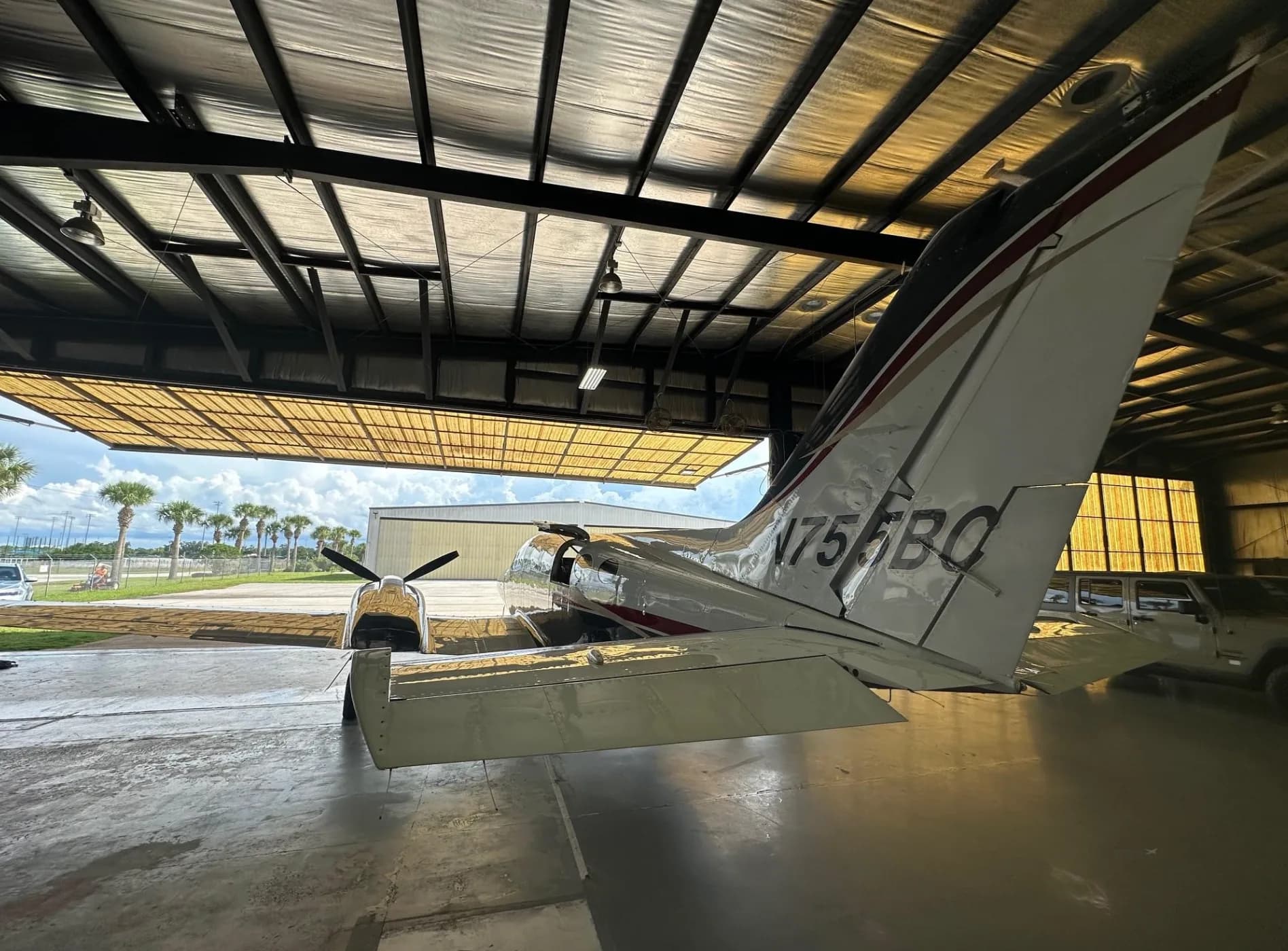 Rear view of the twin-engine aircraft N755BC, with its tail and right wing visible, inside a hangar.