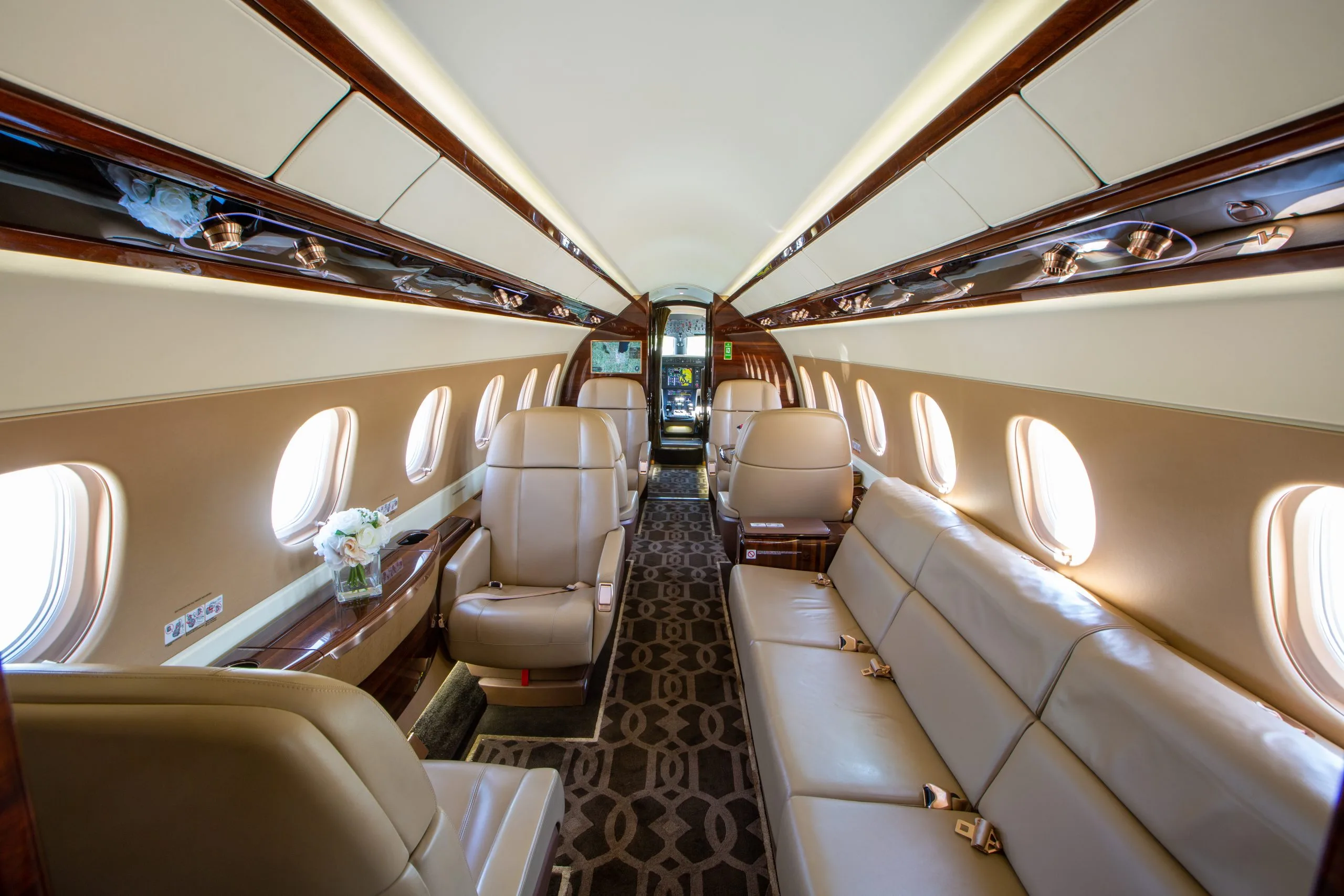 The interior of an Embraer Phenom 300E with leather seats and a sofa.