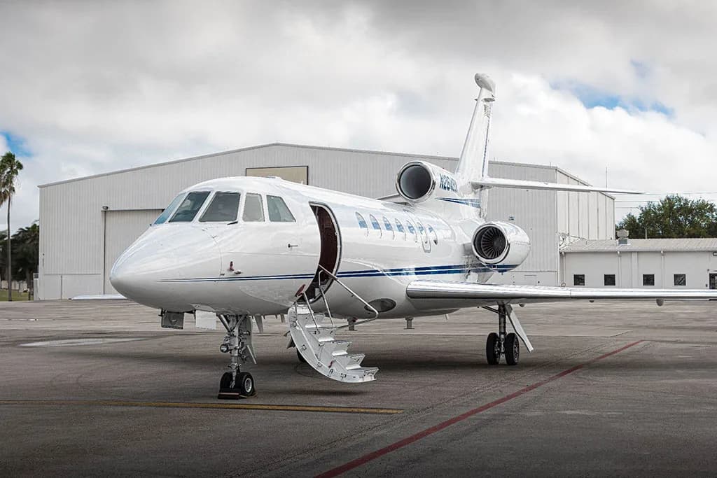 A white business jet with blue stripes, tail number N264RV, parked with its main door open and stairs extended.