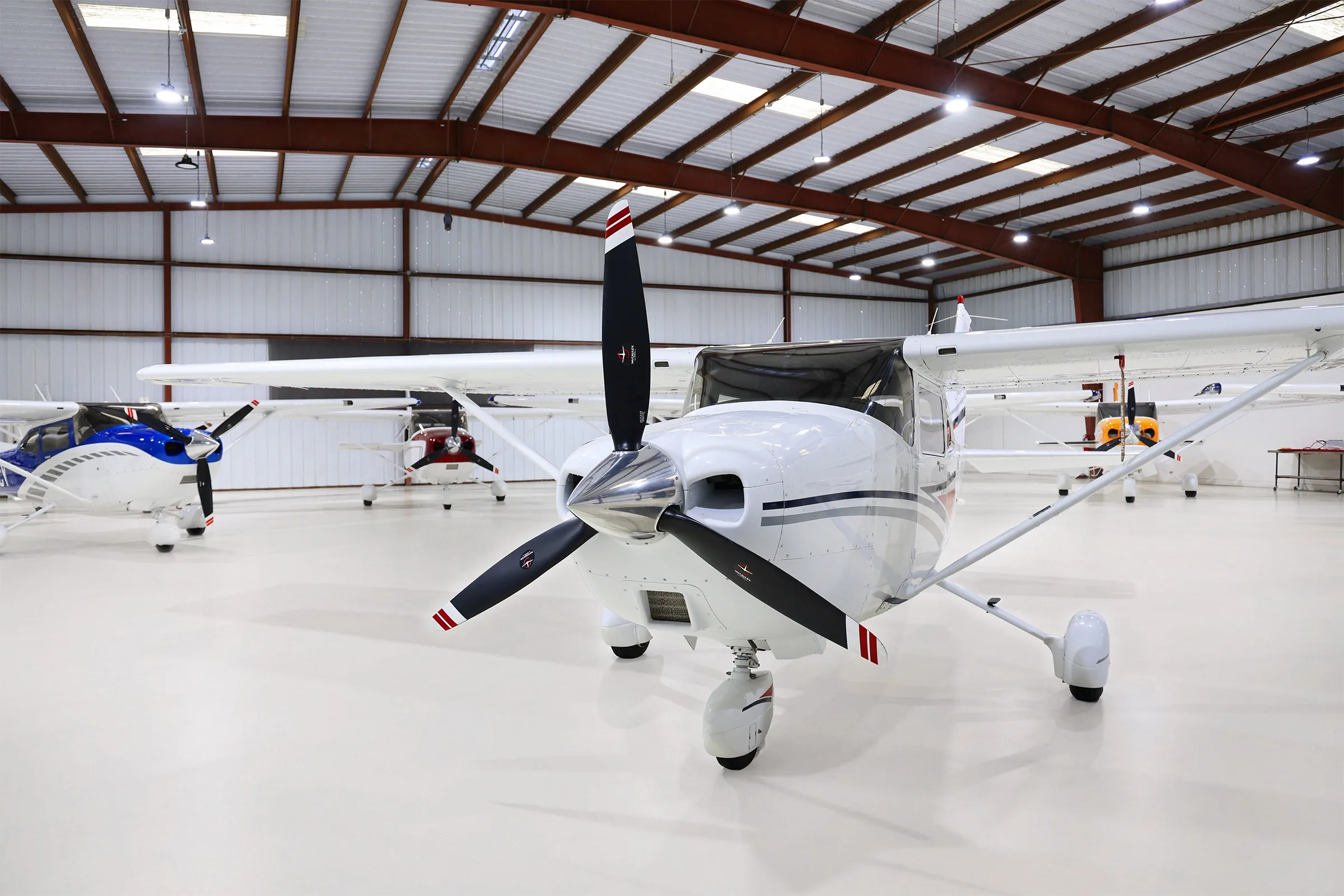 Front view of a white Cessna Skylane N357Z with grey and red stripes, parked in a hangar.