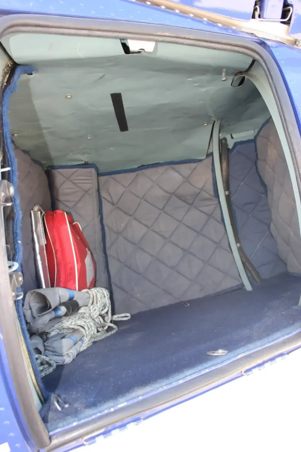 Interior view of the helicopter's storage compartment with a bag and rope.