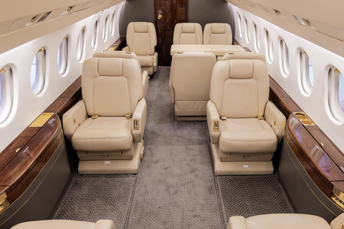 A view of the aircraft's interior, featuring beige leather seats and a central aisle.