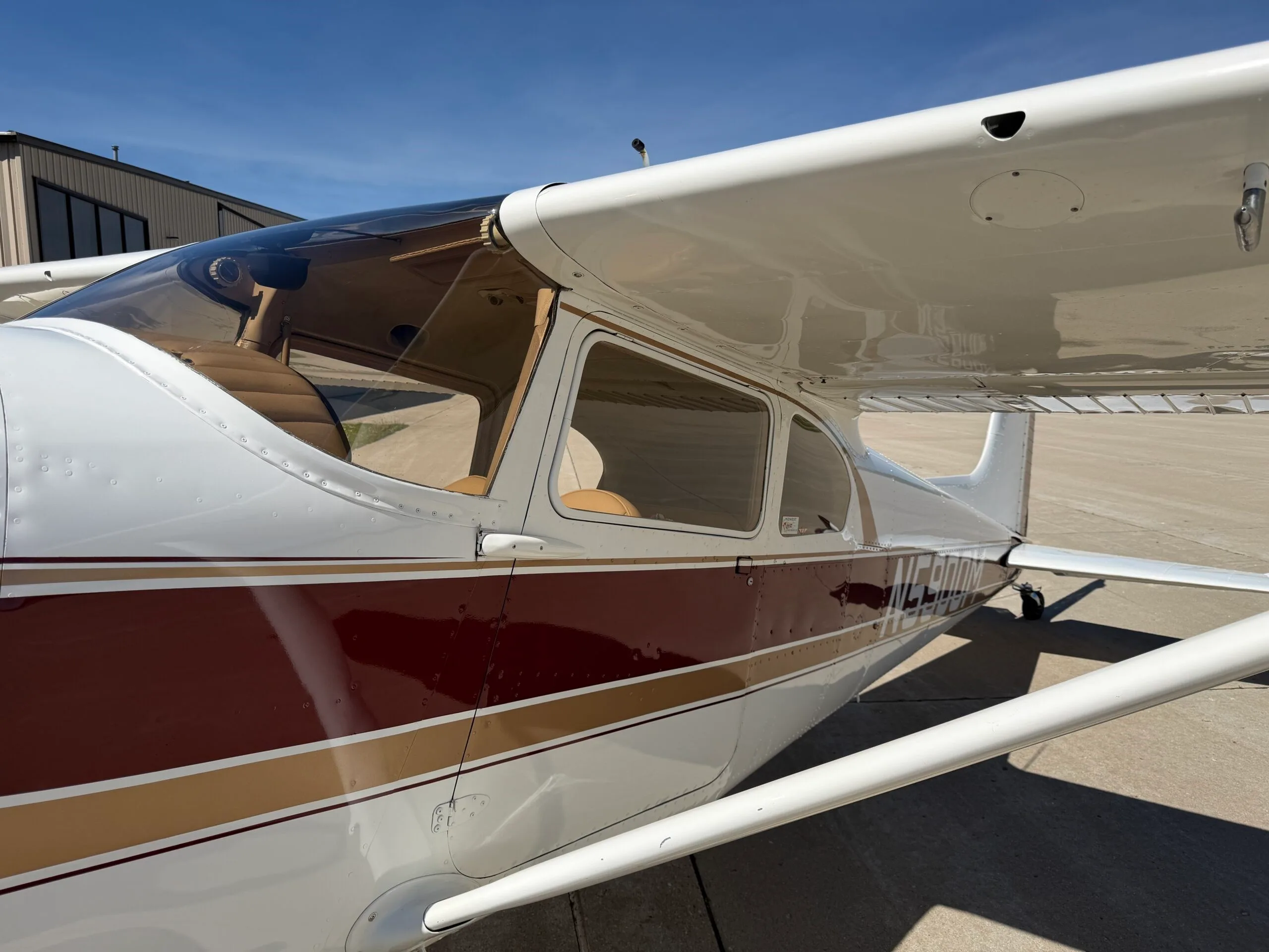 Side view of the cockpit and cabin windows of a white, gold, and maroon Cessna 172.