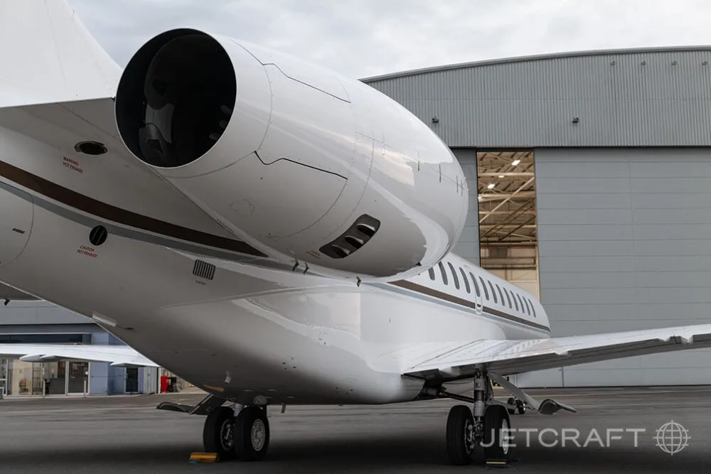 A close-up view of the engine and rear fuselage of a white Bombardier Global business jet, showing the exhaust nozzle.
