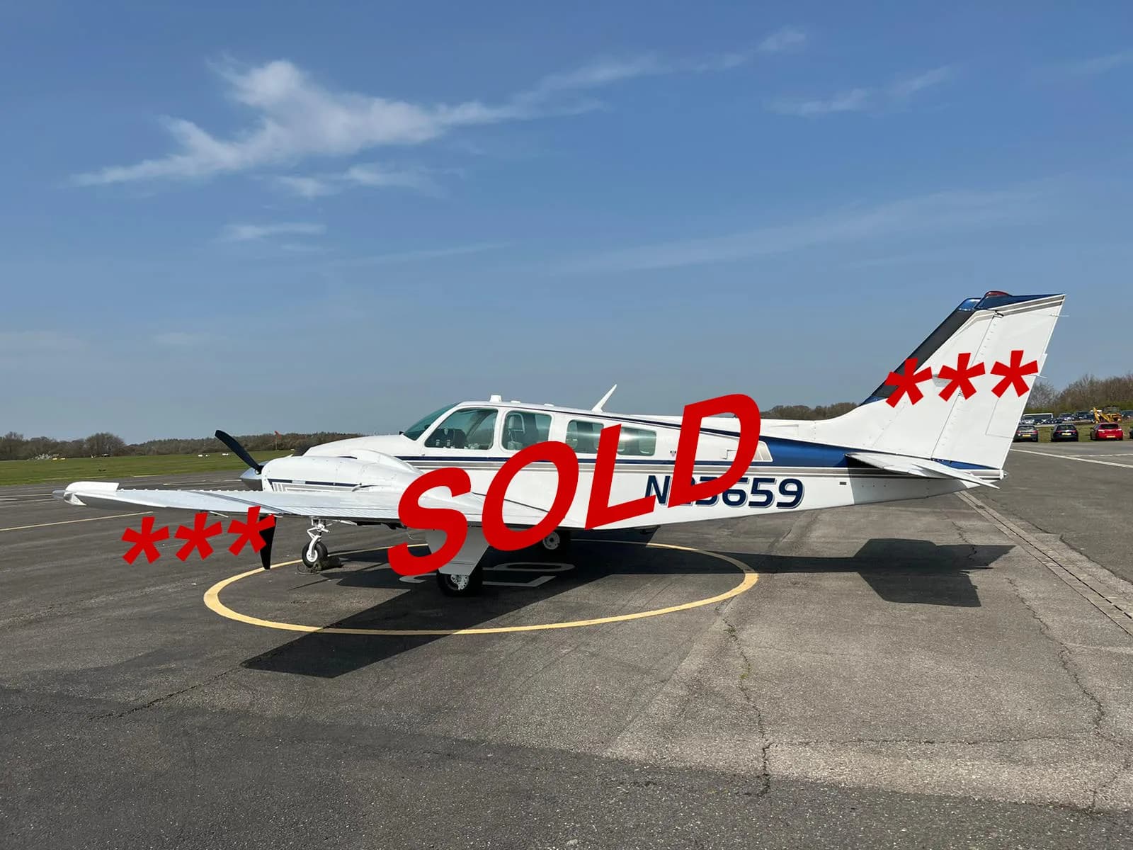 A white single-engine aircraft with a blue stripe, tail number N15659, parked on an airfield.