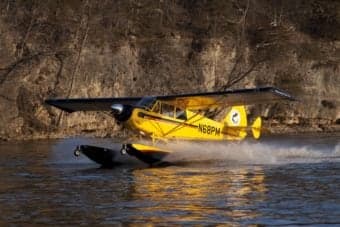 Yellow seaplane taxiing on the water.