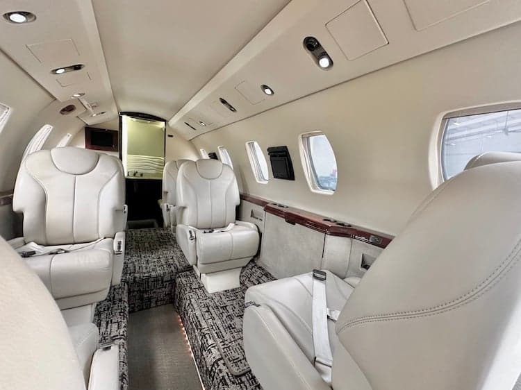 Interior view of the aircraft cabin with leather seats and carpeted floor.