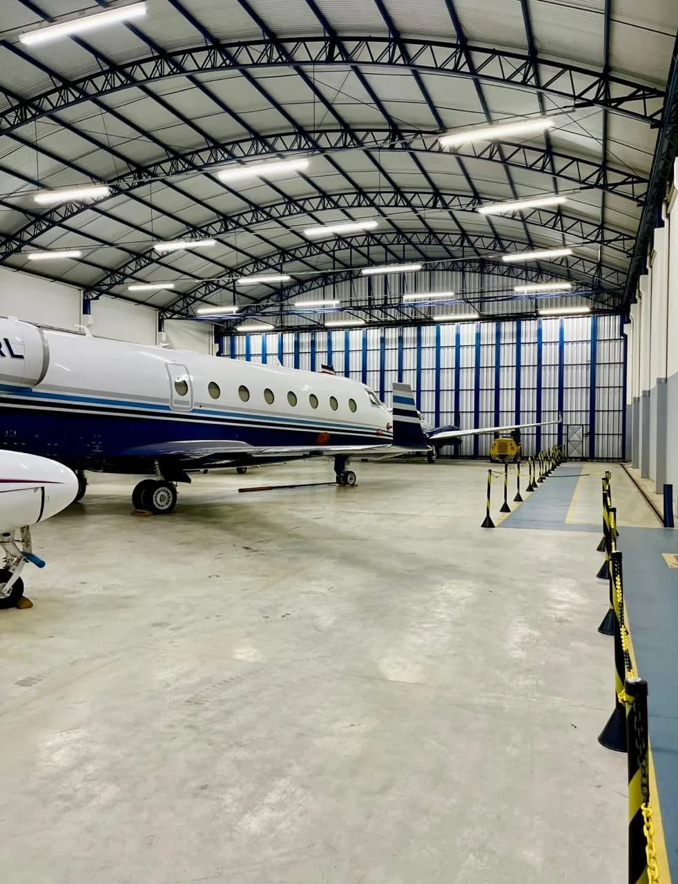 A white and blue business jet parked inside a large hangar.