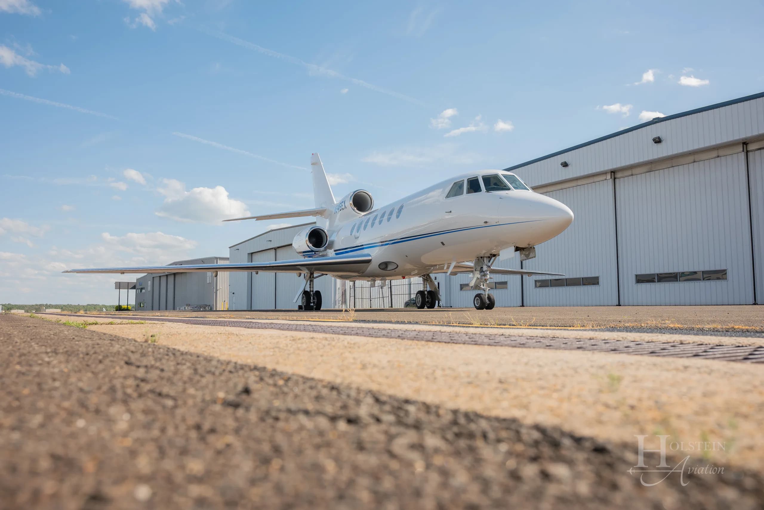 A low-angle front view of the white Dassault Falcon 900EX business jet, N346EX, parked on an airfield.