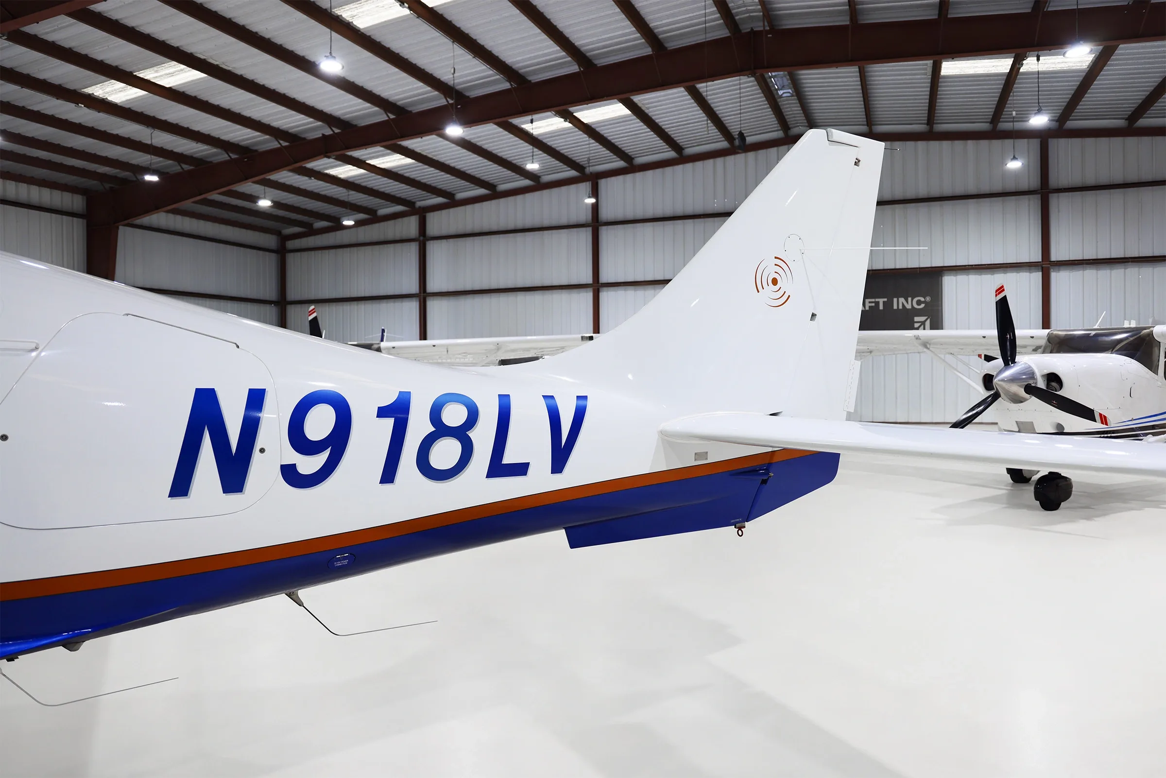 A close-up view of the tail of a white and blue Columbia 400 aircraft, showing the N918LV registration.