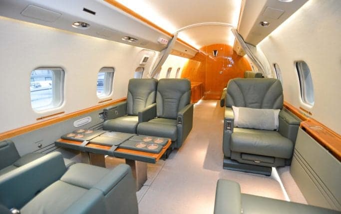 View of the aircraft's interior cabin with leather seats and wood trim.