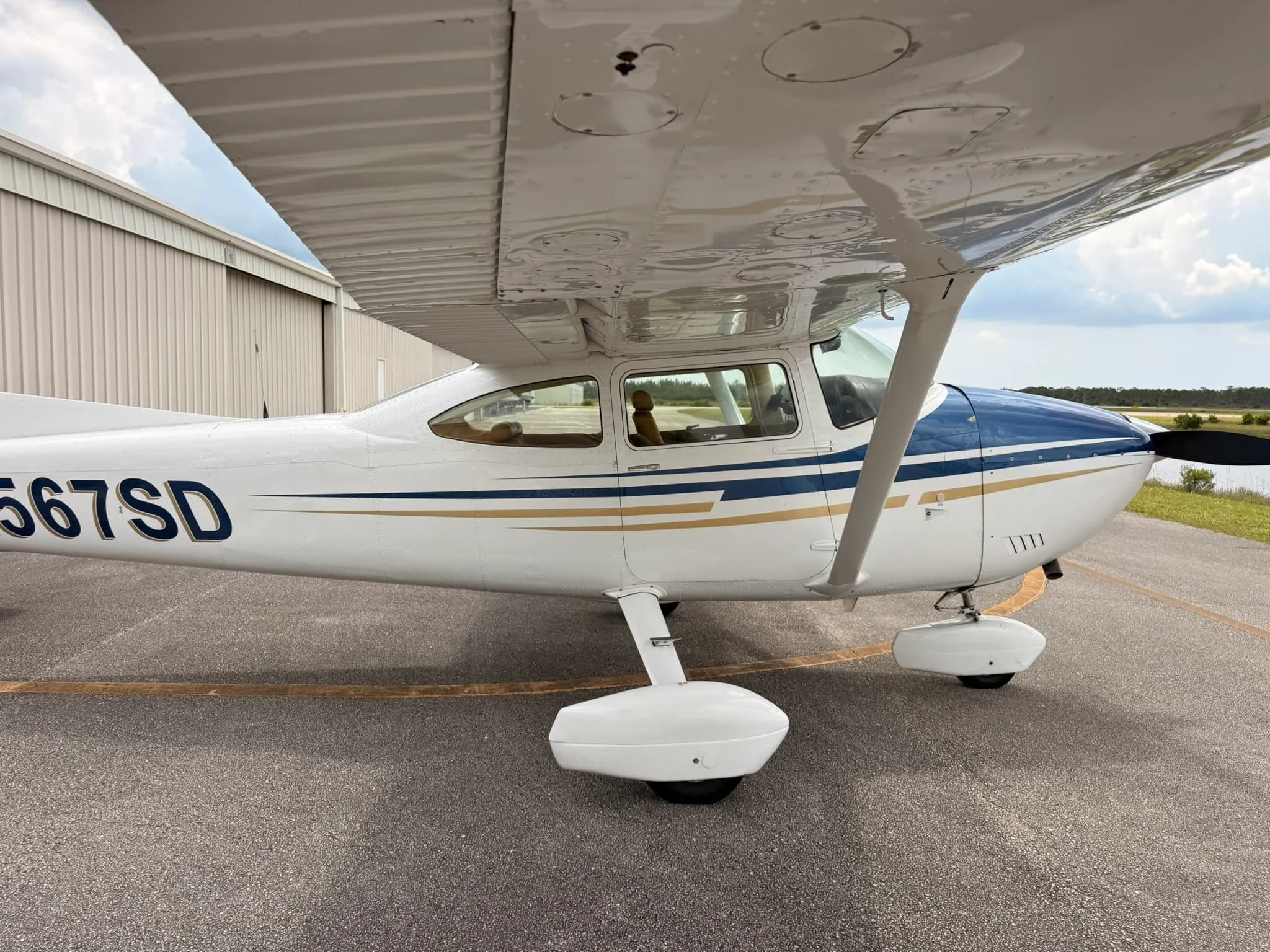 A side view of the fuselage of the Cessna Skylane N567SD, showing the cabin windows and landing gear.