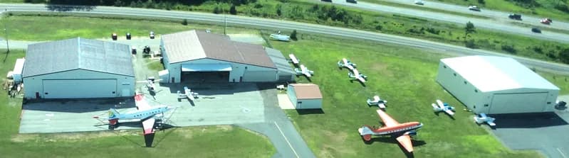 Aerial view of an airport with multiple aircraft parked near hangars.