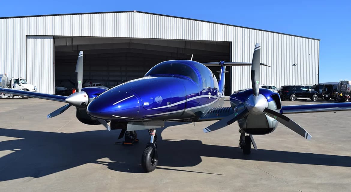 Front view of a Diamond DA62 aircraft with a blue and silver paint scheme parked on the tarmac.