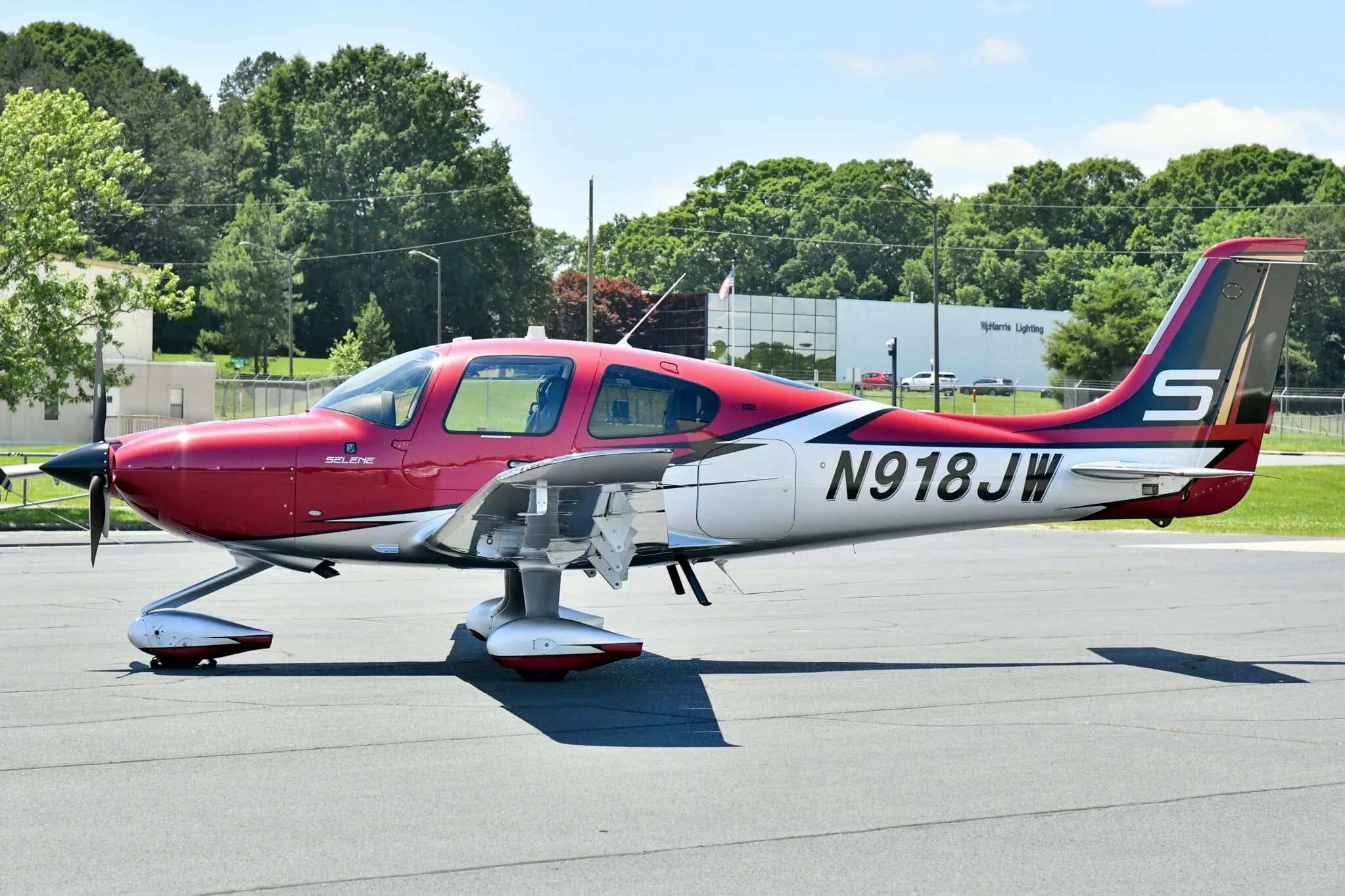 A red and white Cirrus SR22T aircraft with registration N918JW parked on an airfield, viewed from the side.