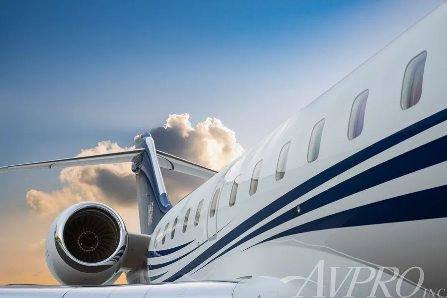 A close-up view of the rear fuselage, engine, and tail of a white and blue business jet.