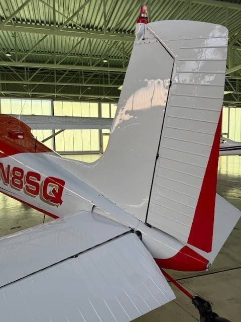 A close-up of the white and red tail section of the Cessna 180/185 aircraft.