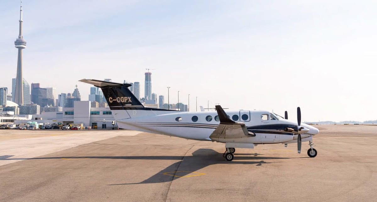 A King Air aircraft with registration C-GGPX is parked on the tarmac with the Toronto skyline in the background.