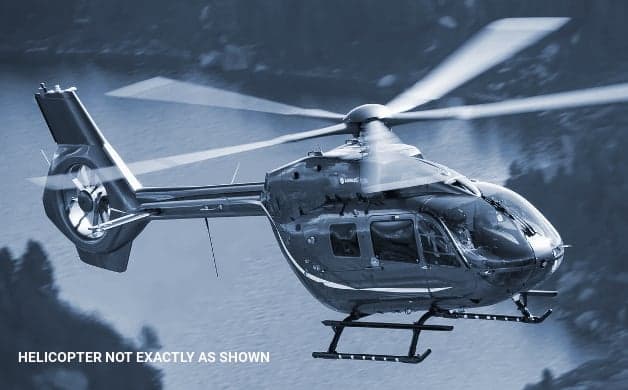 A dark-colored Airbus helicopter in flight over water.