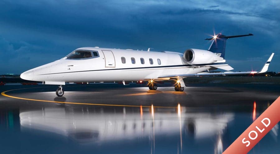 A Learjet aircraft is parked on the tarmac at night.