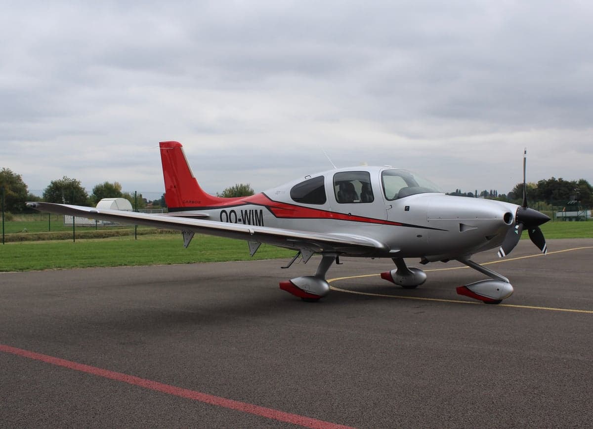 A Cirrus SR22 aircraft with registration OO-WIM is parked on the tarmac.