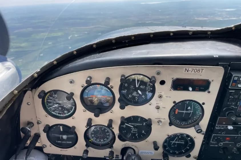 A close-up of the aircraft's instrument panel, showing flight gauges and a view of the landscape from the cockpit.