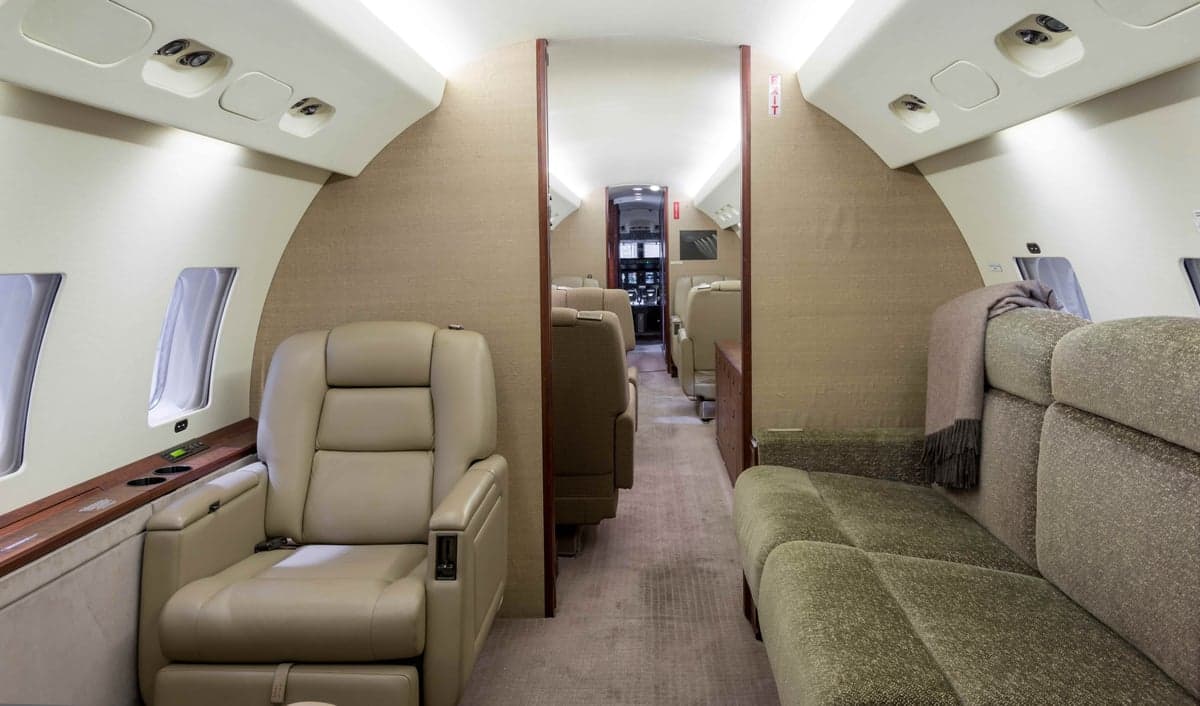 Interior view of the aircraft cabin with seating and a view towards the cockpit.