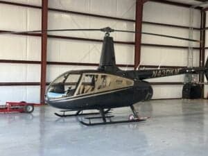 A Robinson R66 helicopter, registration N430KM, sits in a hangar.