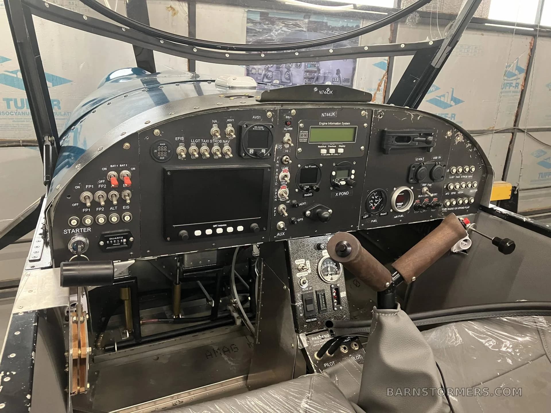A close-up view of the black instrument panel of the Zenith CH650, showing various gauges, switches, and a wooden control stick.