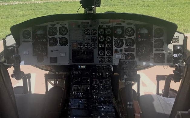 Front view of a white and black Bell 212 helicopter on a helipad.