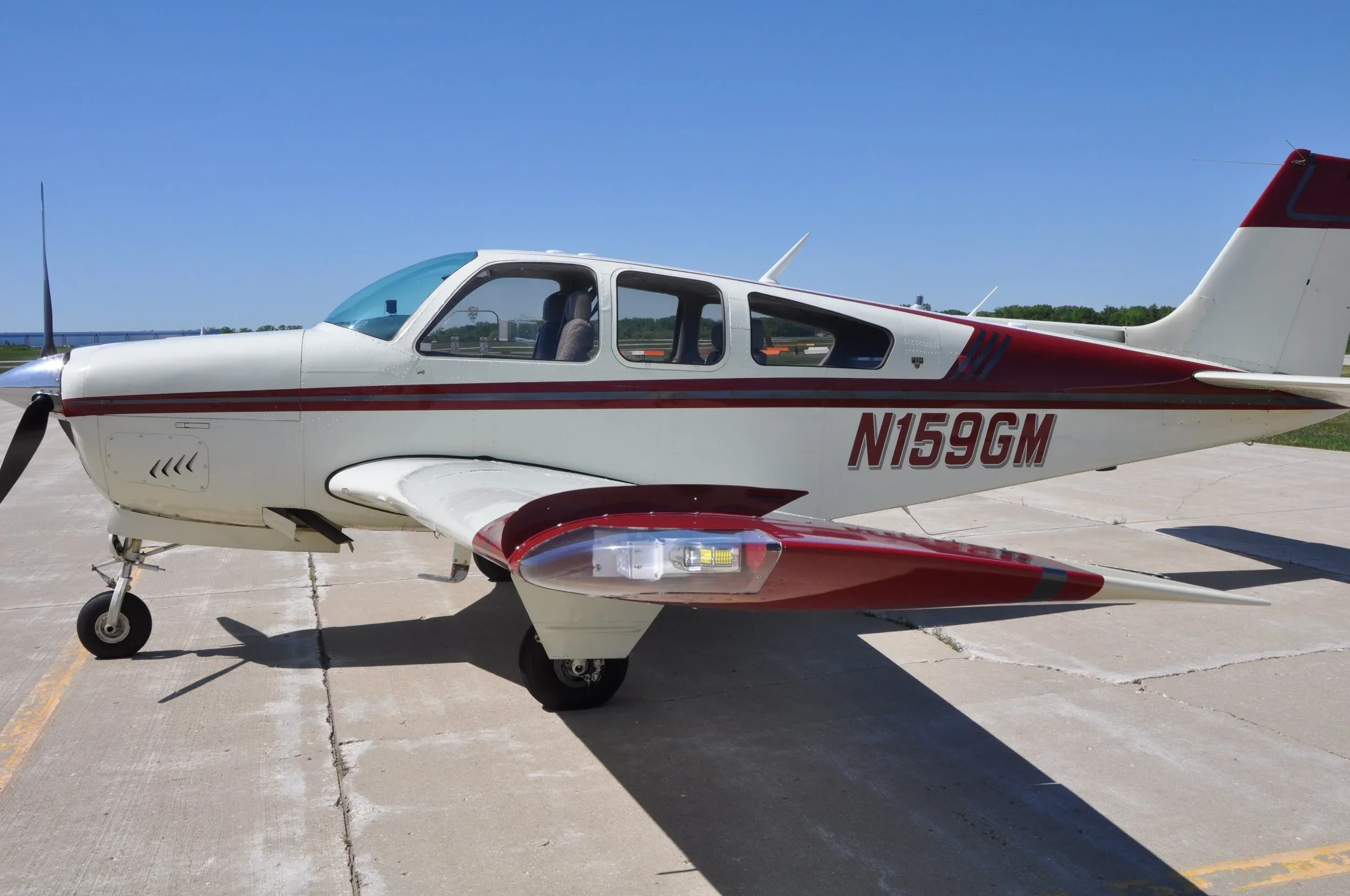 A side view of the white and red aircraft, showing the registration N159GM and a wingtip light.