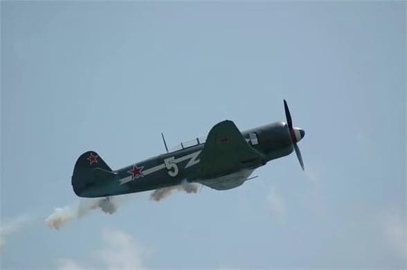 A Lavochkin La-9 in flight with a gray and green paint scheme and a red star on the tail.